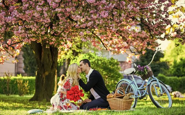 Lovers sensual kissing. Couple in love picnic date. Spring weekend. My treasure. Romantic proposal. Enjoying their perfect date. Couple relaxing in park with bicycle. Romantic picnic with wine - Fotografie, Obrázek