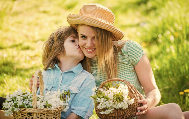 Happy holidays. Mother and cute son wear hats. Family farm. Spring holiday. Wildflowers in field. Motherhood happiness. Cowboy family collecting flowers in baskets. Lovely family nature background - Foto, afbeelding