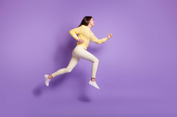 Full length side angle photo portrait of girl running jumping up isolated on vivid violet colored background - Фото, зображення
