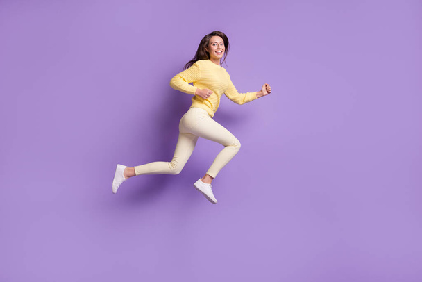 Full length photo portrait of woman running smiling jumping up isolated on bright purple colored background - Foto, afbeelding