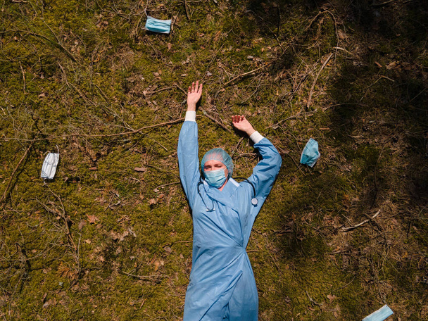 Moe vrouwelijke arts of verpleegkundige rust in het bos na vermoeiende diensten - Foto, afbeelding