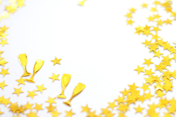 Festive background. Shining confetti stars and glass of champagne on white background. Christmas. Wedding. Birthday. Happy woman`s day. Mothers Day. Valentine`s Day. Flat lay, top view, copy space - Photo, Image