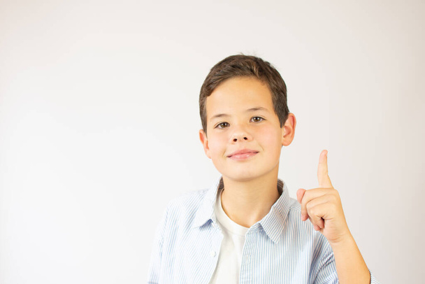 A handsome young boy in the blue shirt holds his thumb up - 写真・画像