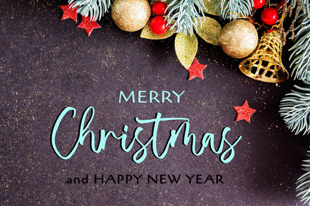 Christmas card with congratulations and pine branches with decor on a dark background with glitter - Photo, Image
