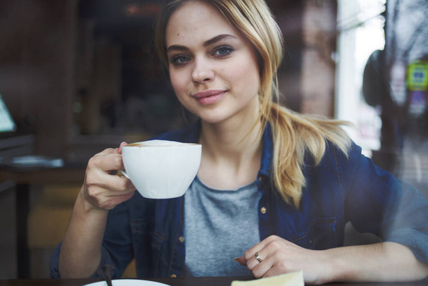 Vrouw met een kop koffie in een restaurant vakantie socialiseren ontbijt levensstijl - Foto, afbeelding