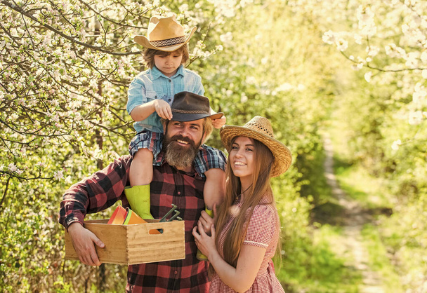 Hobby brings them joy. Happy family in spring garden. Family hobby. Bearded man and woman with child hold gardeners tools. Hobby and leisure activity. Gardening is great hobby. Pastime and relaxation - Foto, Bild