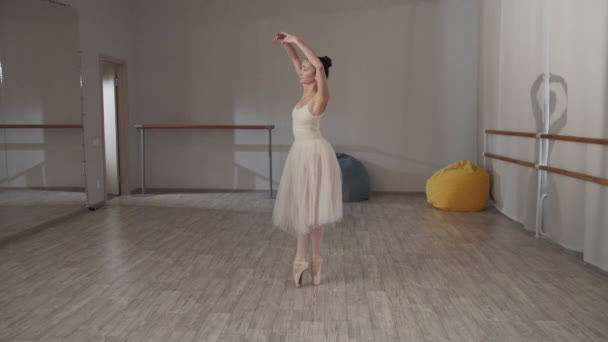 Καλαίσθητη μπαλαρίνα στην αίθουσα χορού μπροστά από τον καθρέφτη σε ένα όμορφο φόρεμα κάνει πιρουέτες - Πλάνα, βίντεο