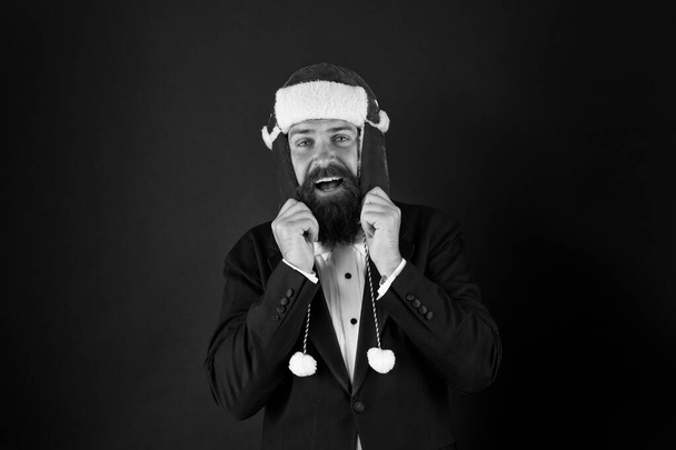This hat warms his ears. Happy businessman wear santa hat. Bearded man smile in hat with earflaps and faux fur. Fashion accessory for Christmas. Warm and stylish trapper hat for santa party - Фото, зображення