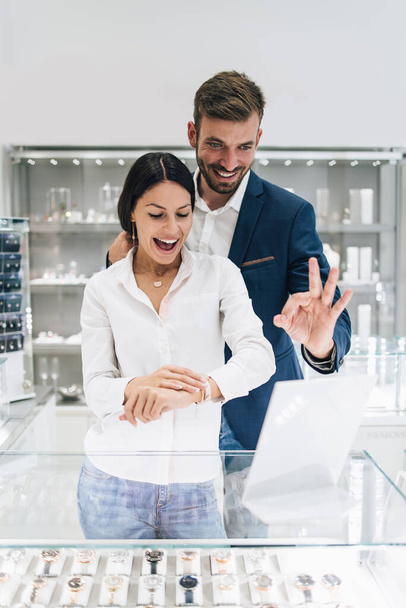 Beautiful couple enjoying in shopping at modern jewelry store. Close up shot of woman's hand with gorgeous expensive ring and bracelet. - Фото, зображення