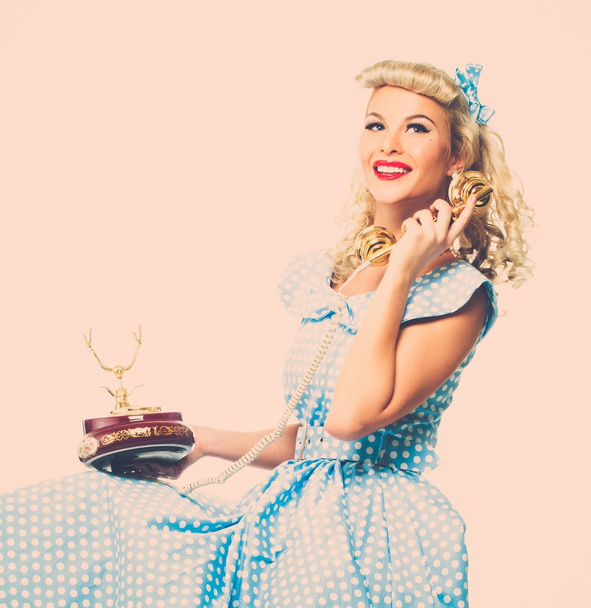 Coquette blond pin-up stijl jonge vrouw in blauwe jurk met vintage telefoon  - Foto, afbeelding