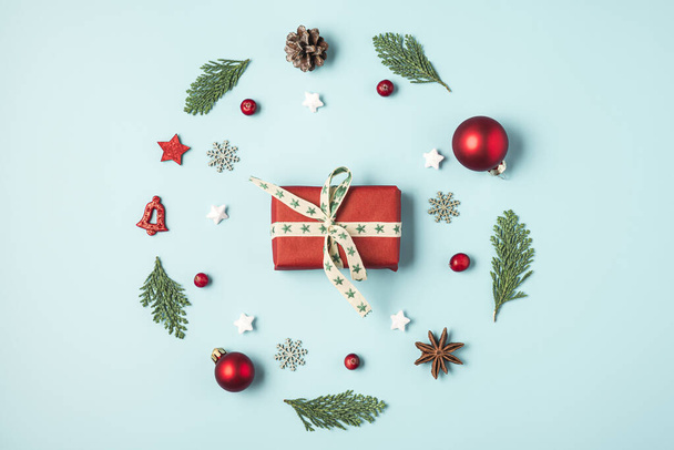 Χριστούγεννα ή Ευτυχισμένο το Νέο Έτος σύνθεση από κλαδιά έλατο δέντρο, διακοσμήσεις διακοπών και κουτί δώρου σε μπλε φόντο. επίπεδη θέσει. πάνω όψη - Φωτογραφία, εικόνα