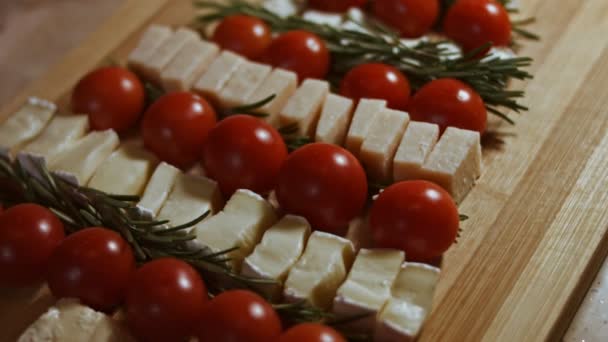 Flat lay of cheese and tomatoes. Slices of cheese, tomatoes and rozmarin arranged in a shape of Christmas Tree. Food for Christmas holiday. Rotation. Slowmotion - Footage, Video