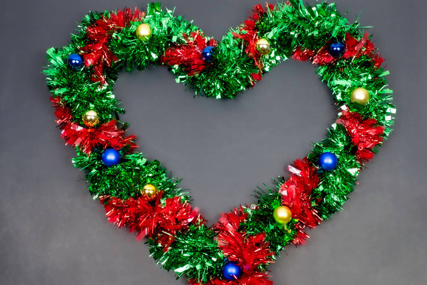 Karácsonyi határ sablon fenyő ágak, szív alakú, Gyönyörű piros zöld kék és arany játékok és szalag, a tér szürke háttér, Boldog karácsonyt és boldog új évet. - Fotó, kép