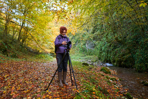 Woman nature photographer with professional camera hiking by the river - Fotografie, Obrázek