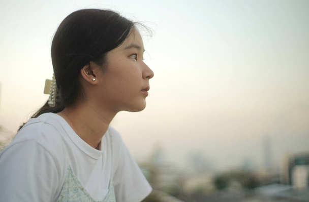Νεαρό κορίτσι της ασιατικής χιλιετίας κοιτάζει έξω από τη θέα του ουρανού ηλιοβασιλέματος, συναισθηματική αίσθηση, ήρεμη και ειρηνική φόντο  - Φωτογραφία, εικόνα