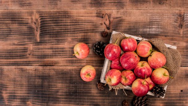 Organic ripe red apples in wooden box. Fall harvest cornucopia in autumn season. Fresh fruit with wood table background. - Valokuva, kuva