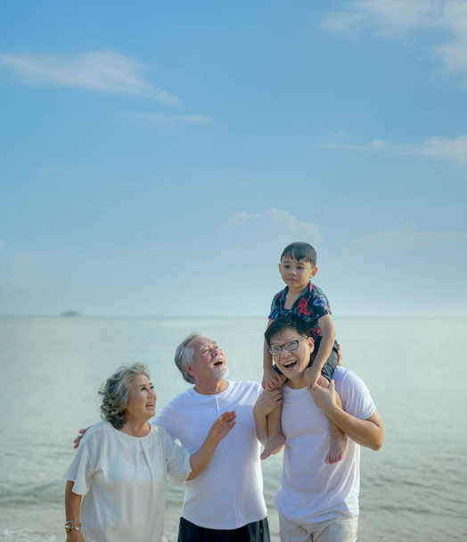 Ασιατική μεγάλη οικογένεια ταξιδεύουν μαζί στην παραλία. Ηλικία συνταξιοδότησης με το γιο και το εγγόνι χαλάρωση και αναψυχή στις καλοκαιρινές διακοπές. - Φωτογραφία, εικόνα