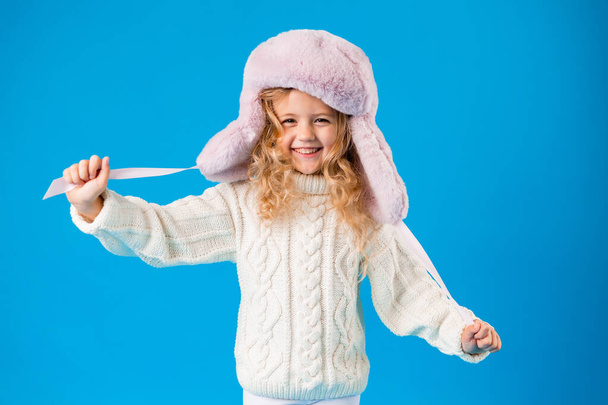 portrait of smiling little girl in winter hat and knitted sweater - Photo, Image
