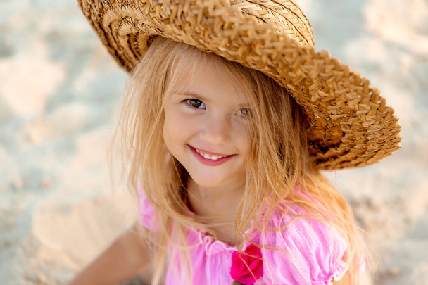 κοντινό πορτρέτο του μικρού χαμογελαστού κοριτσιού που φοράει ψάθινο καπέλο - Φωτογραφία, εικόνα