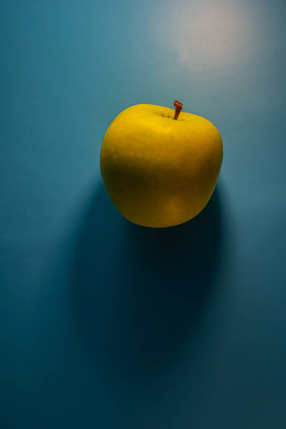 green apple lies on a blue background. Background for design. - Φωτογραφία, εικόνα