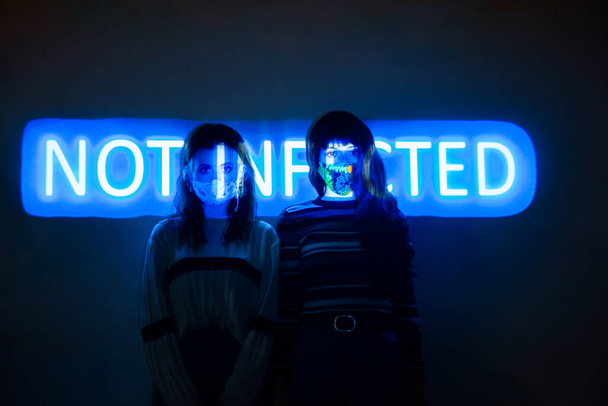 Zwei Frauen an der Wand mit der nicht infizierten Botschaft, die auf ihren Körper projiziert wird - Foto, Bild