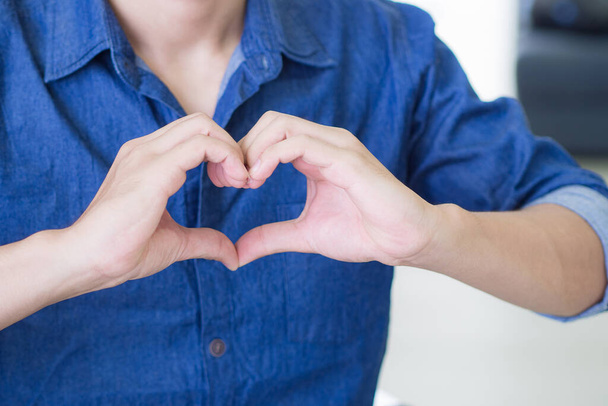 Close-up de um jovem fazendo uma forma de coração com os dedos. Espaço para SMS. Conceito de celebrar o Dia dos Namorados. - Foto, Imagem