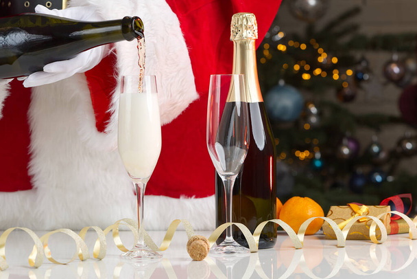 Santa claus dress adult pouring out champagne. pouring sparkling wine by glasses, celebration, start of the holiday, success concept - Photo, Image