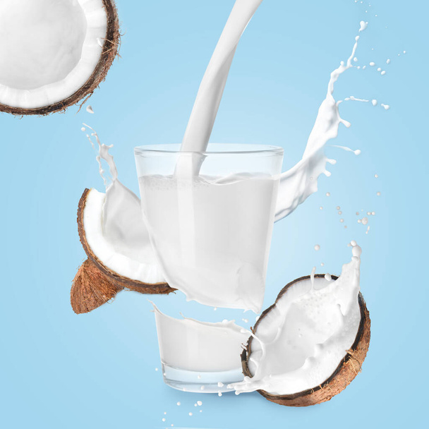 Glass of coconut milk with splashes on color background   - Photo, Image