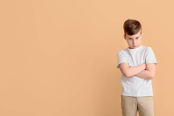 Suspicious cute boy with crossed arms on color background - Foto, Imagen