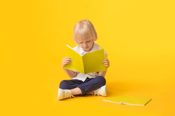 Netter kleiner Junge mit Notizbüchern auf farbigem Hintergrund - Foto, Bild