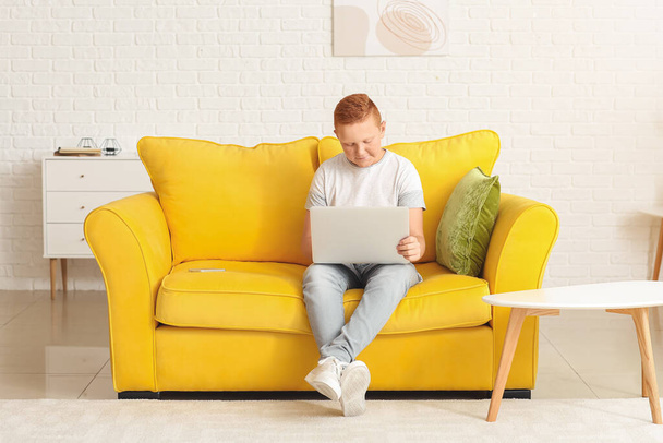 Teenage chlapec s notebookem sedí na pohovce doma - Fotografie, Obrázek