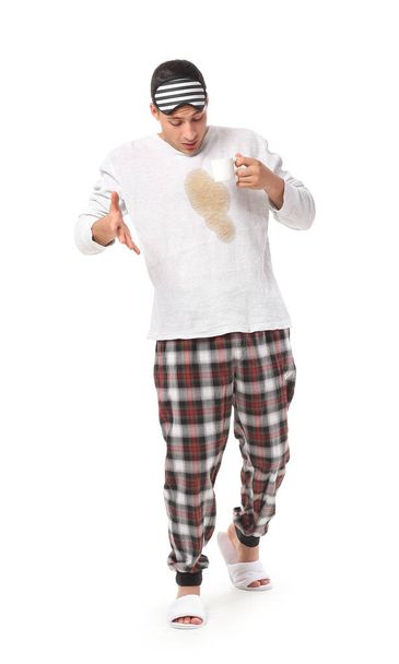 Stresszes fiatalember kávé foltok a pizsamája tetején fehér háttér - Fotó, kép