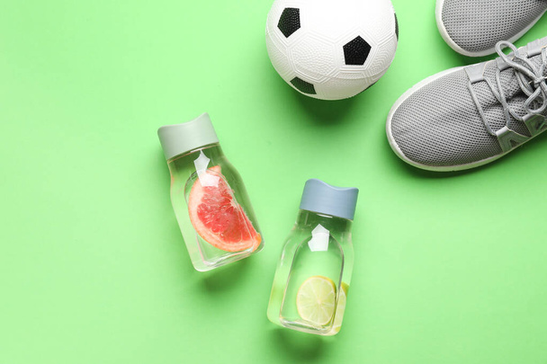 Бутылки влитой воды, спортивная обувь и футбольный мяч на цветном фоне - Фото, изображение