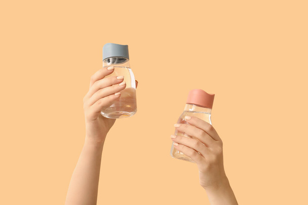 Manos femeninas y botellas de agua sobre fondo de color - Foto, imagen