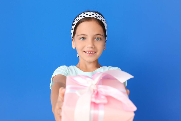 Cute little girl with gift on color background - Valokuva, kuva