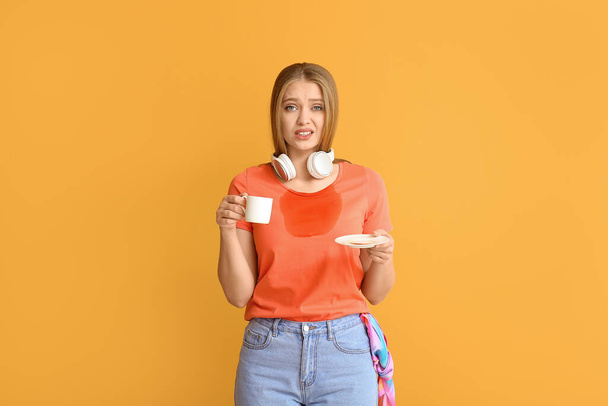 Troubled young woman with coffee stains on her t-shirt on color background - Foto, Imagem