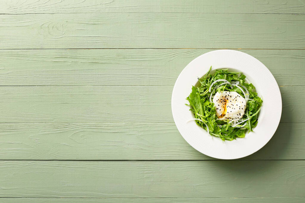 Plate with tasty arugula salad on wooden background - Фото, изображение