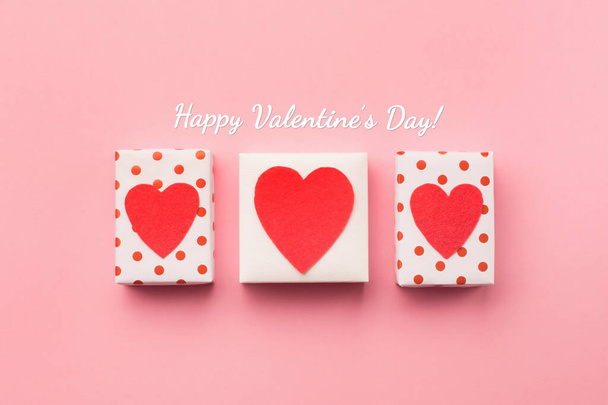 Valentinstag Komposition. Weiße Geschenkboxen mit Schleife und roten Filzherzen auf rosa Hintergrund. Ansicht von oben.  - Foto, Bild