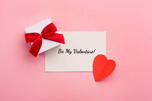 Valentijnsdag, bruiloft of andere vakantie compositie. Handgemaakte geschenkdoos en rode hartjes op roze achtergrond met kopieerruimte voor tekst. Vlakke plaat - Foto, afbeelding