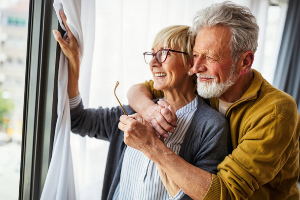 Happy senior couple hugging and enjoying retirement at home - Фото, изображение