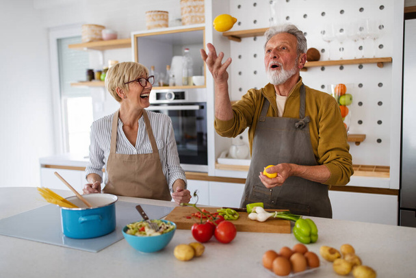Senior couple having fun and cooking together in kitchen at home - Photo, Image