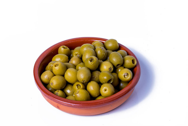 Un sacco di olive farcite con acciughe in una ciotola di ceramica e sfondo bianco - Foto, immagini