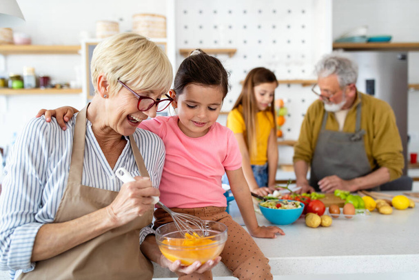 Cheerful family spending good time together while cooking in kitchen. Grandparents, grandchildren concept. - Photo, image