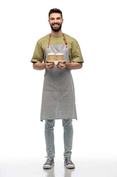 happy smiling barman in apron with takeaway coffee - Zdjęcie, obraz