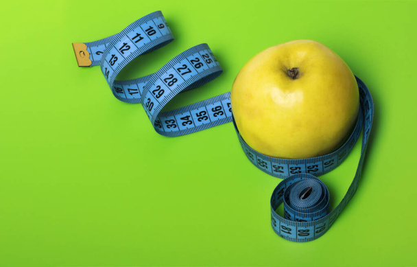 жовте яблуко з синьою вимірювальною стрічкою на зеленому фоні дієта і спортивна концепція з копією простору
. - Фото, зображення