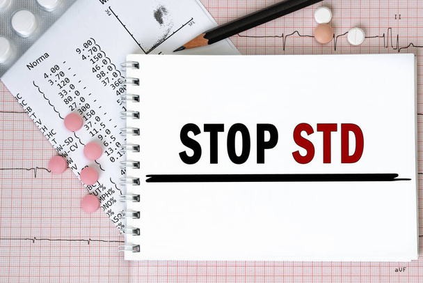 Página de caderno com palavras - STOP STD (Doenças sexualmente transmissíveis) nas proximidades com um comprimido e lápis, conceito médico, vista superior - Foto, Imagem