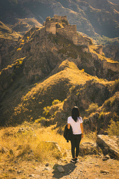 mujer se para y mira a la fortaleza de Tmogvi en el fondo. Turismo en el Cáucaso. Aventura de viaje en solitario. - Foto, Imagen