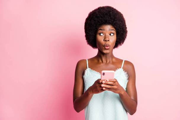 Фотографія коричневого волосся чарівна дівчина виглядає порожнім простором тримайте телефонний спільний телефон після одягу синглет ізольовано на фоні рожевого кольору
 - Фото, зображення