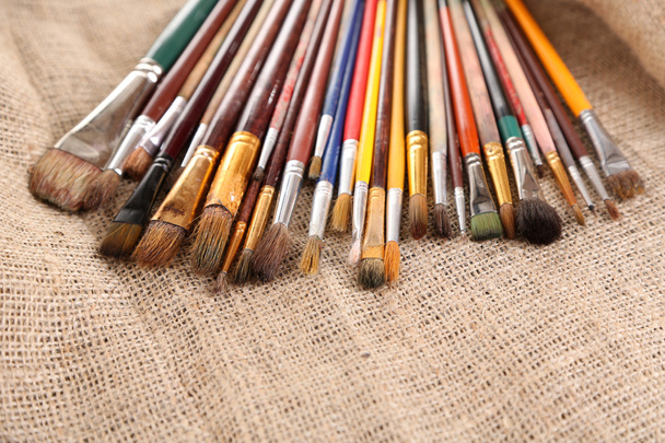 Many brushes in paints on sackcloth background - Foto, Bild