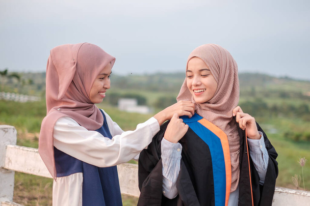 Krásná asijská žena muslimské studenty montáž maturitní šaty a pózoval ve štěstí před promoce obřad. - Fotografie, Obrázek